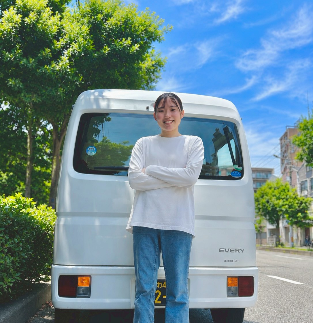 軽バンの前で笑顔を見せるひとつホールディングスのスタッフ